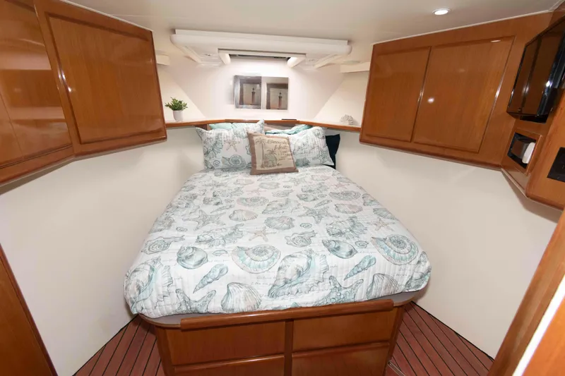 Slide: The Image of Cozy bedroom in 1999 Viking 60 Cockpit Motor Yacht with wooden cabinets and patterned bedding. - 34
