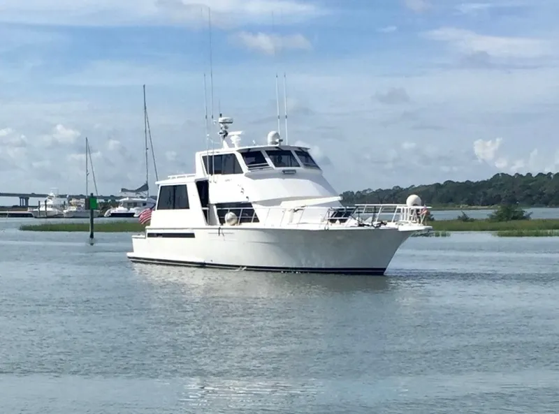 Slide: The Image of 1999 Viking 60 Cockpit Motor Yacht on calm water, with scenic background. - 4
