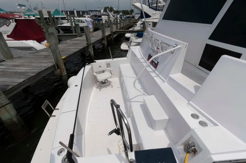 Slide: The Image of 1999 Viking 60 Cockpit Motor Yacht docked, showcasing spacious deck and seating area. - 8