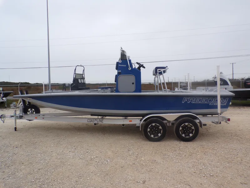 Slide: The Image of 2025 Freedom Warrior 23 boat on trailer, blue and gray design, parked outdoors. - 1