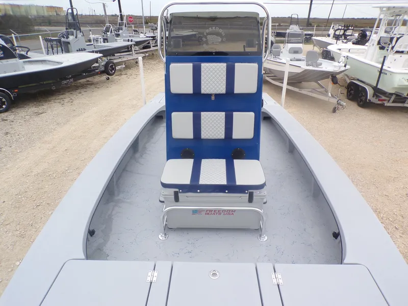 Slide: The Image of 2025 Freedom Warrior 23 boat with blue and white seating, displayed outdoors. - 14