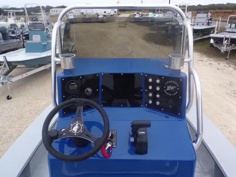 Slide: The Image of Control panel of a 2025 Freedom Warrior 23 boat, featuring steering wheel and dashboard controls. - 23