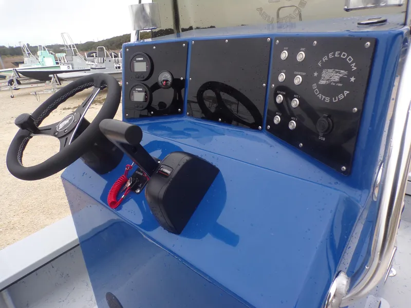 Slide: The Image of Control panel of a 2025 Freedom Warrior 23 boat with steering wheel and gauges. - 26