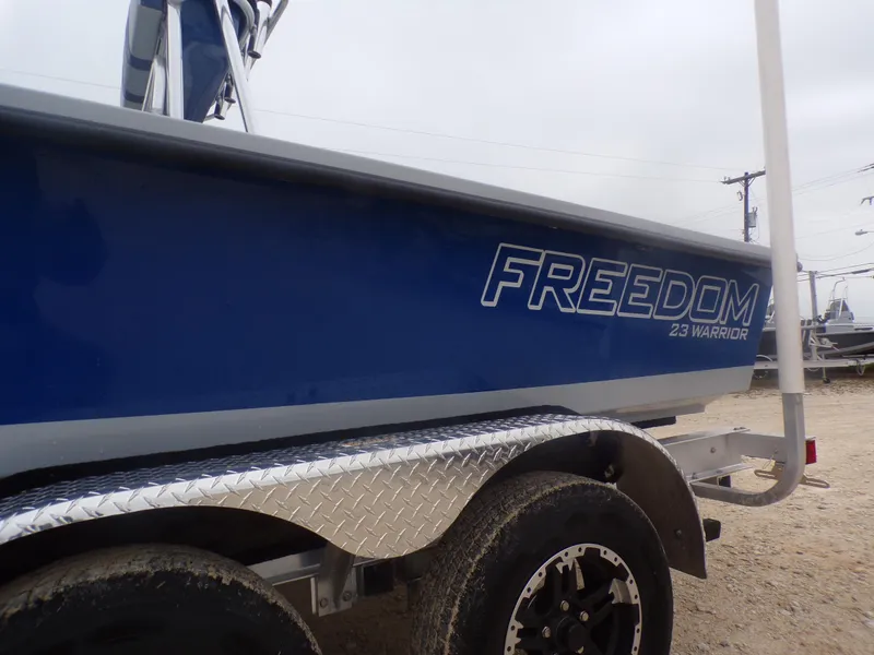 Slide: The Image of 2025 Freedom Warrior 23 boat on trailer, blue hull, outdoor setting. - 34