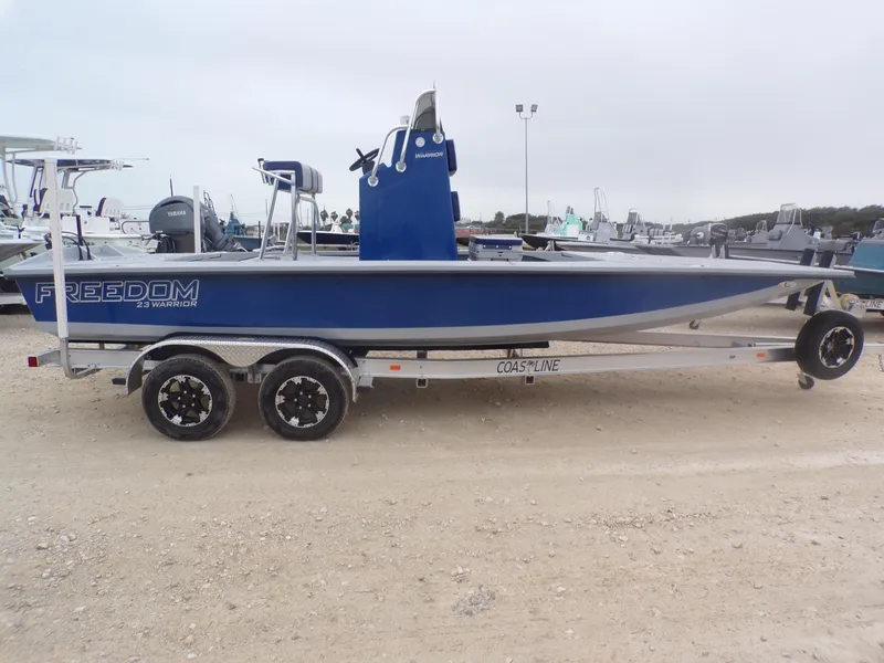 Slide: The Image of 2025 Freedom Warrior 23 boat on trailer, blue hull, parked outdoors. - 8