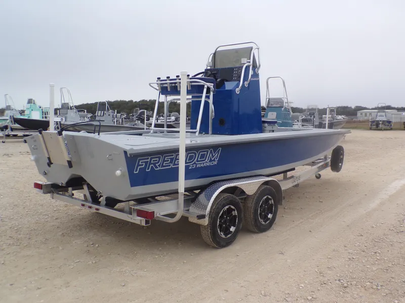 Slide: The Image of 2025 Freedom Warrior 23 boat on trailer, blue and silver design, parked outdoors. - 9