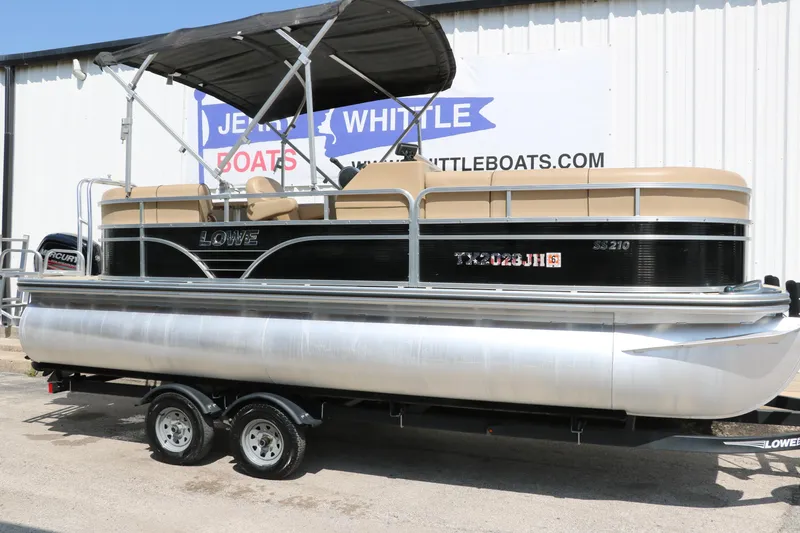Slide: The Image of 2019 Lowe SS210 pontoon boat with canopy on trailer, parked outside dealership. - 1