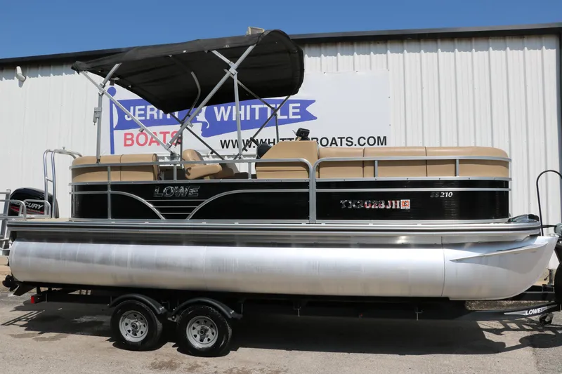 Slide: The Image of 2019 Lowe SS210 pontoon boat with canopy on trailer, parked outside dealership. - 13
