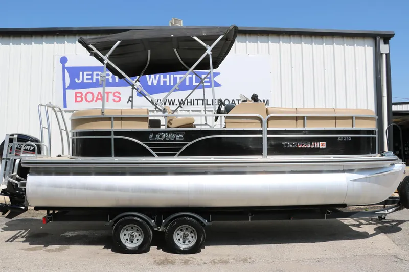 Slide: The Image of 2019 Lowe SS210 pontoon boat with canopy on trailer, parked outside dealership. - 14