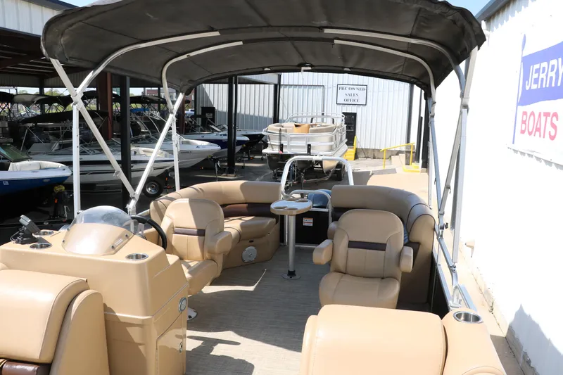 Slide: The Image of 2019 Lowe SS210 pontoon boat with tan seating and canopy in a boat dealership. - 20