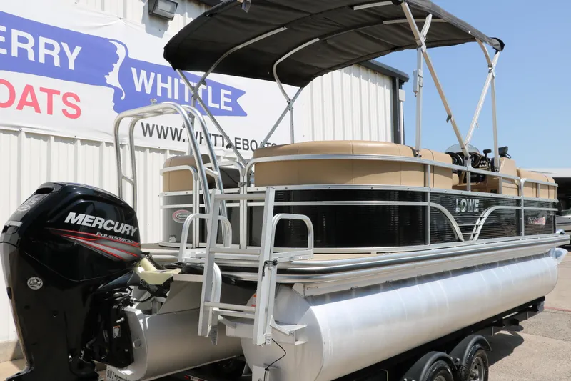 Slide: The Image of 2019 Lowe SS210 pontoon boat with Mercury outboard motor, parked near a dealership. - 3