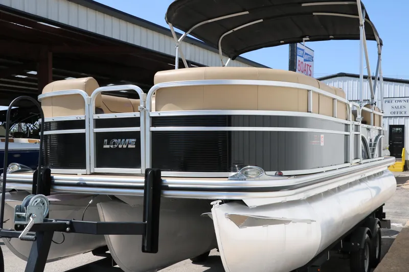 Slide: The Image of 2019 Lowe SS210 pontoon boat with canopy, parked on trailer at dealership. - 7