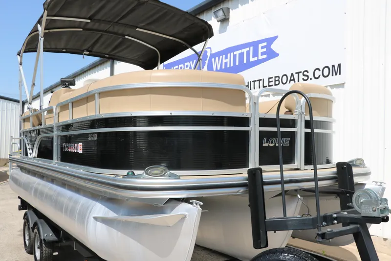 Slide: The Image of 2019 Lowe SS210 pontoon boat on trailer, black and beige design, at dealership. - 9