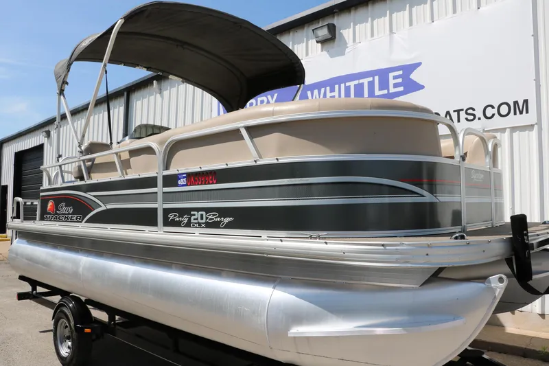 Slide: The Image of 2015 Sun Tracker Party Barge 20 DLX pontoon boat on trailer, parked outside a building. - 11