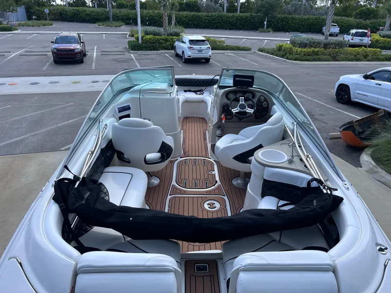 Slide: The Image of 2004 Four Winns 240 Horizon boat with spacious seating and sleek design in a parking lot. - 11