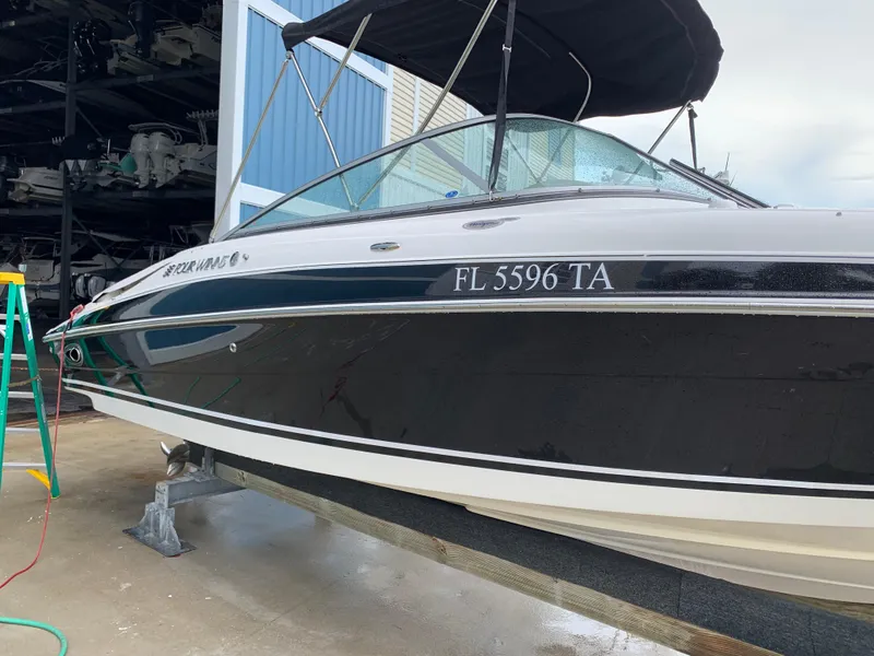 Slide: The Image of 2004 Four Winns 240 Horizon boat with black hull, docked and covered. - 2