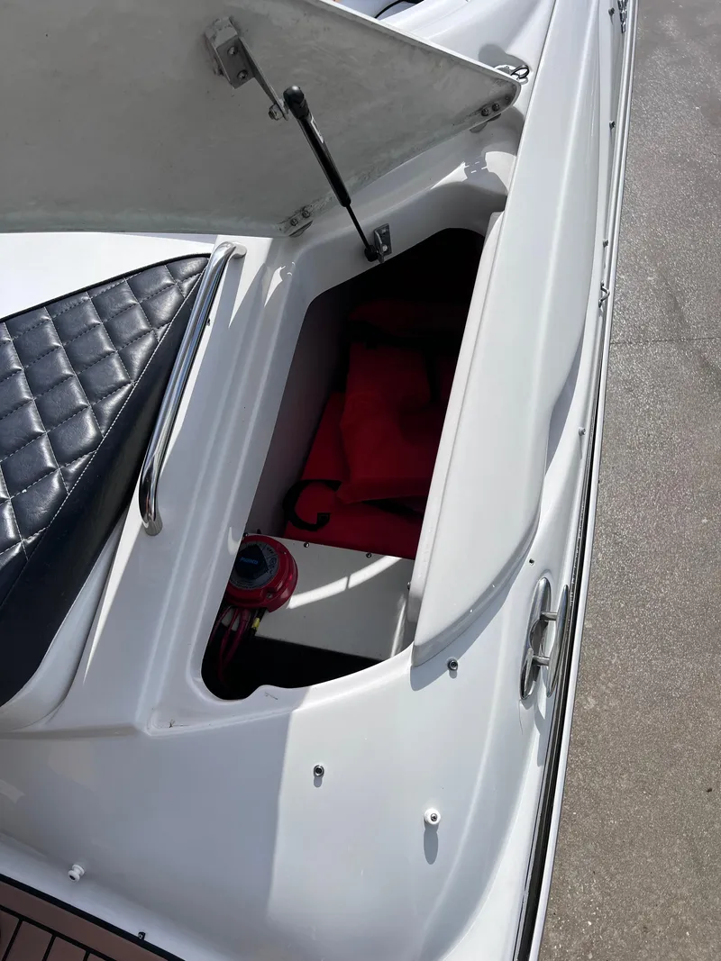 Slide: The Image of 2004 Four Winns 240 Horizon boat storage compartment with open lid, revealing interior items. - 9