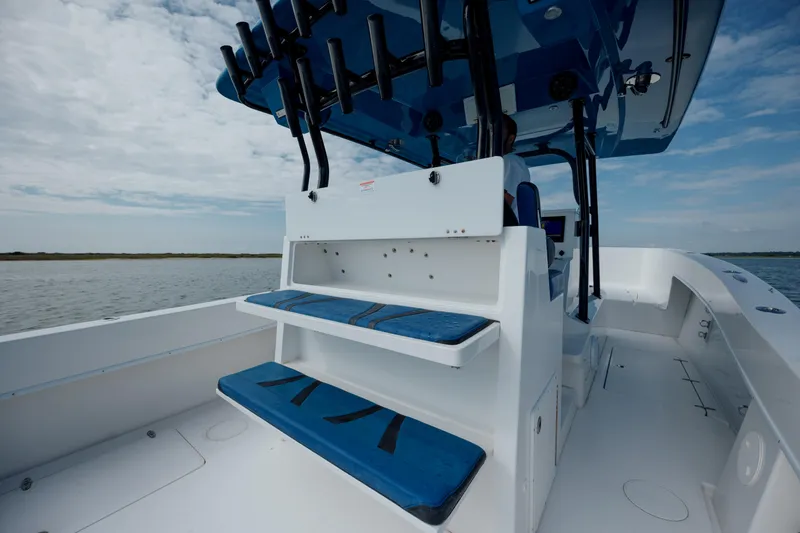 Slide: The Image of 2020 Prowler 31 boat interior with blue seating and rod holders on a calm water backdrop. - 14