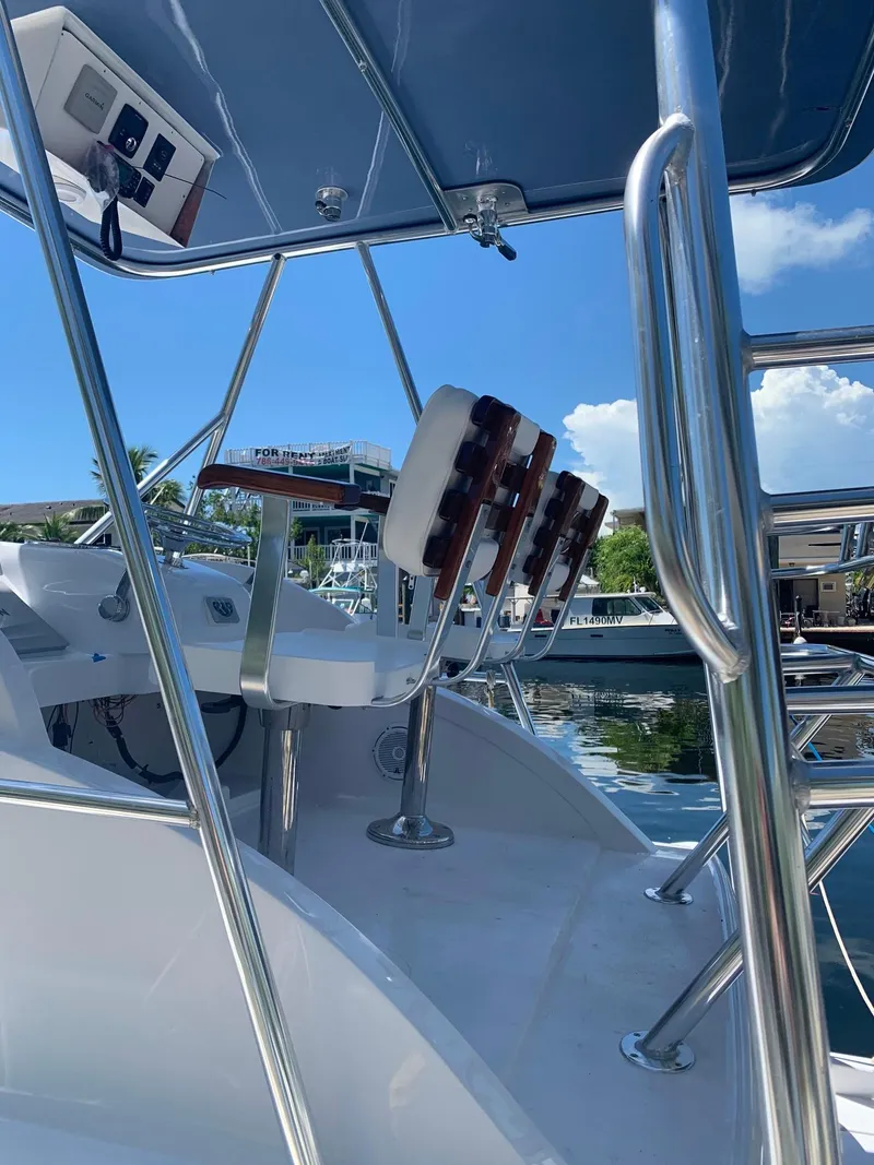 Slide: The Image of 1974 Bertram 31 Flybridge Cruiser with helm and seating, docked under clear blue sky. - 11