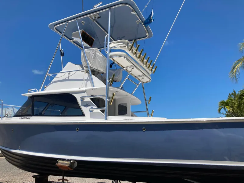 Slide: The Image of 1974 Bertram 31 Flybridge Cruiser with blue hull and fishing tower under clear sky. - 18