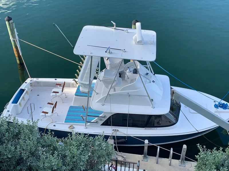 Slide: The Image of 1974 Bertram 31 Flybridge Cruiser docked, aerial view, with striped deck chairs. - 2