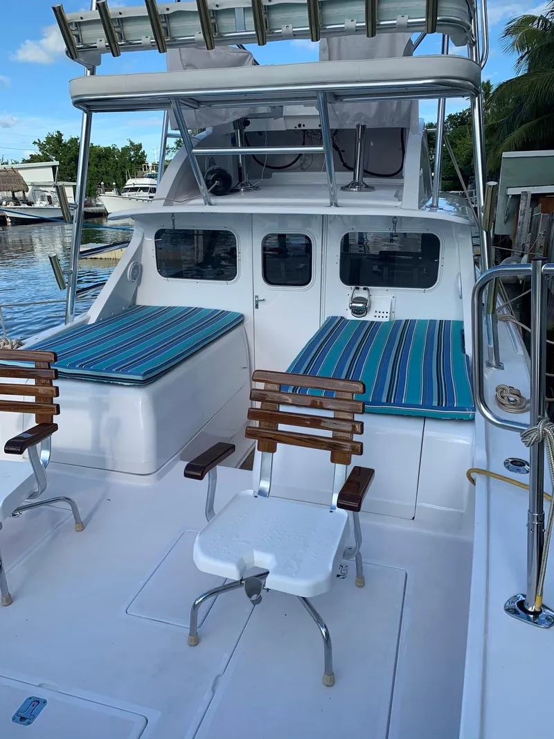 Slide: The Image of 1974 Bertram 31 Flybridge Cruiser with striped seating, docked by the water. - 4