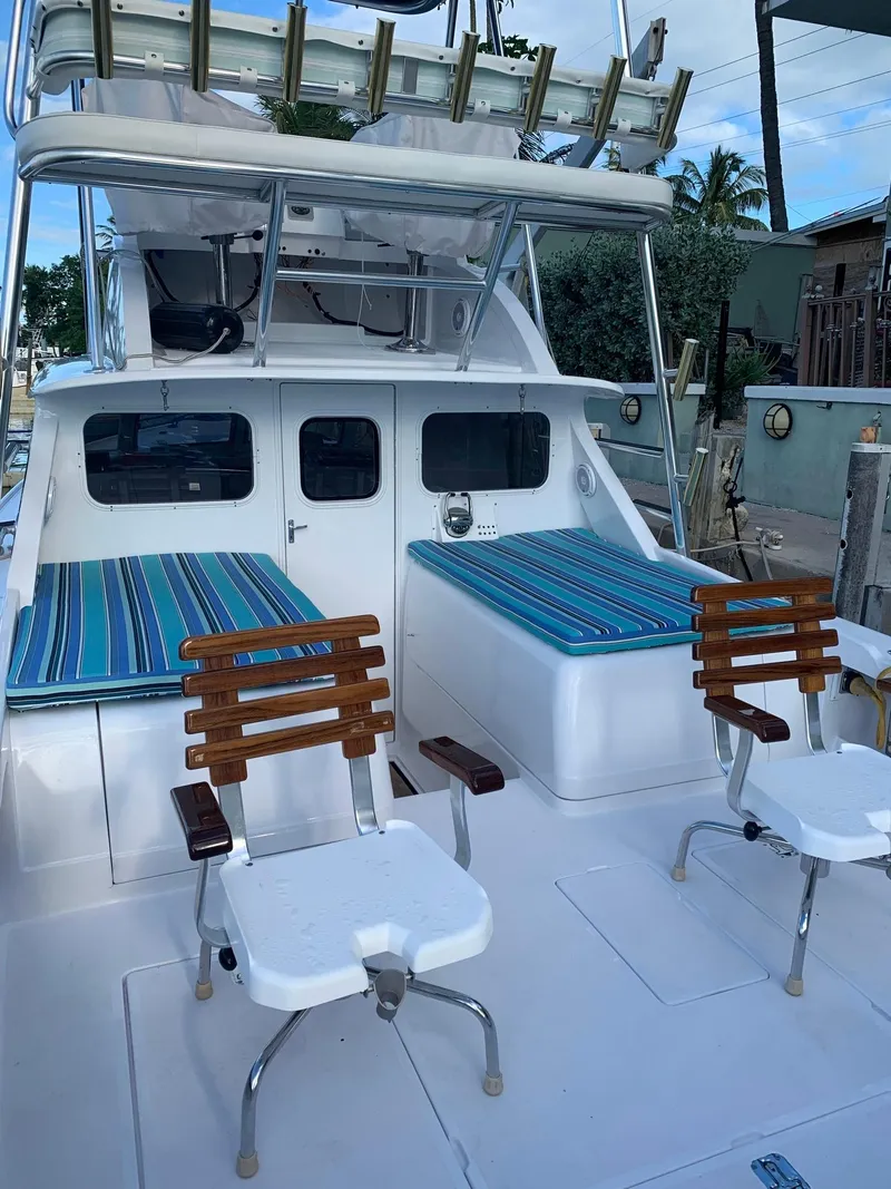 Slide: The Image of 1974 Bertram 31 Flybridge Cruiser with striped seating and fishing chairs on deck. - 5