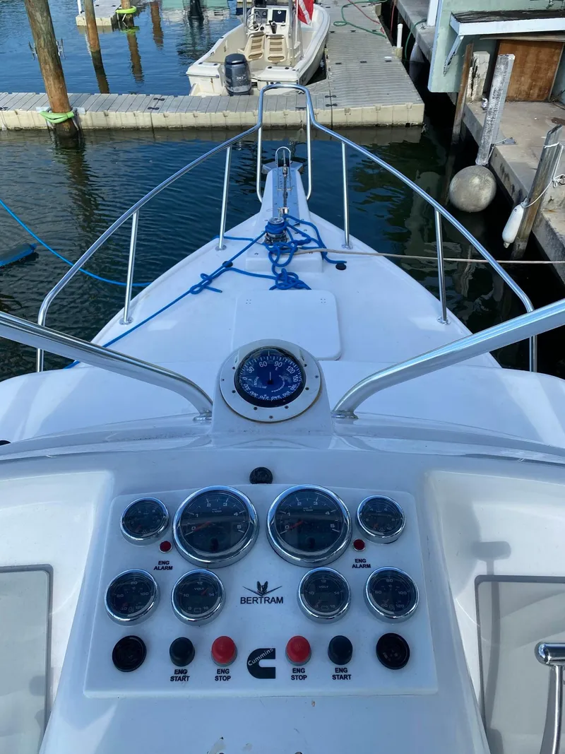 Slide: The Image of 1974 Bertram 31 Flybridge Cruiser dashboard with gauges, docked at marina. - 6