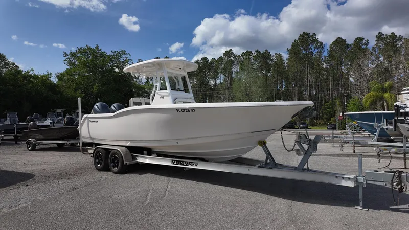 Slide: The Image of 2020 Tidewater 252 CC Adventure boat on trailer, parked outdoors under a blue sky. - 0