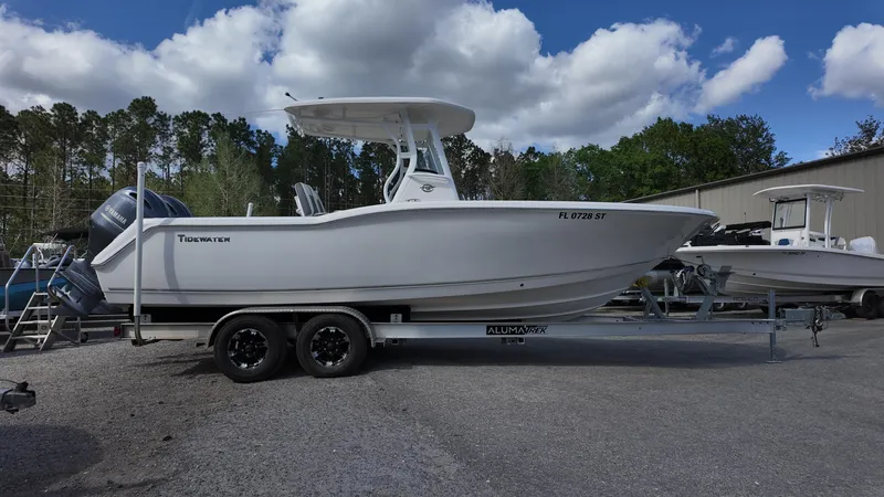 Slide: The Image of 2020 Tidewater 252 CC Adventure boat on trailer, parked outdoors under cloudy sky. - 12