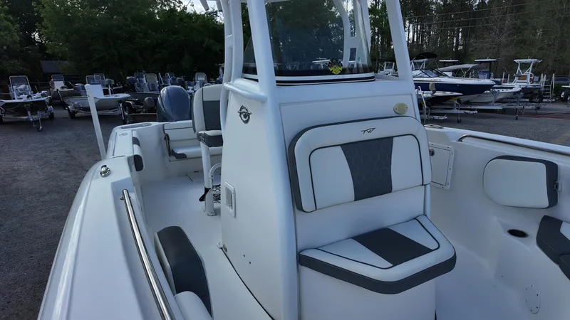 Slide: The Image of 2020 Tidewater 252 CC Adventure boat interior with seating and console, parked outdoors. - 25