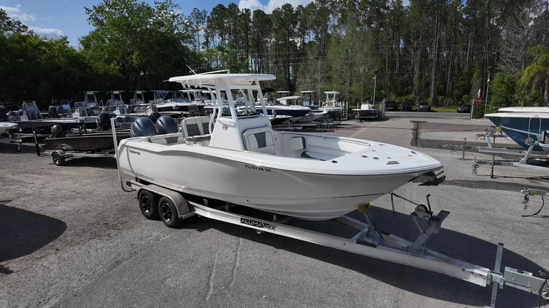 Slide: The Image of 2020 Tidewater 252 CC Adventure boat on trailer, parked outdoors with trees in background. - 6