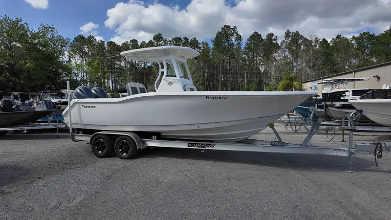 Slide: The Image of 2020 Tidewater 252 CC Adventure boat on trailer, parked outdoors under cloudy sky. - 9
