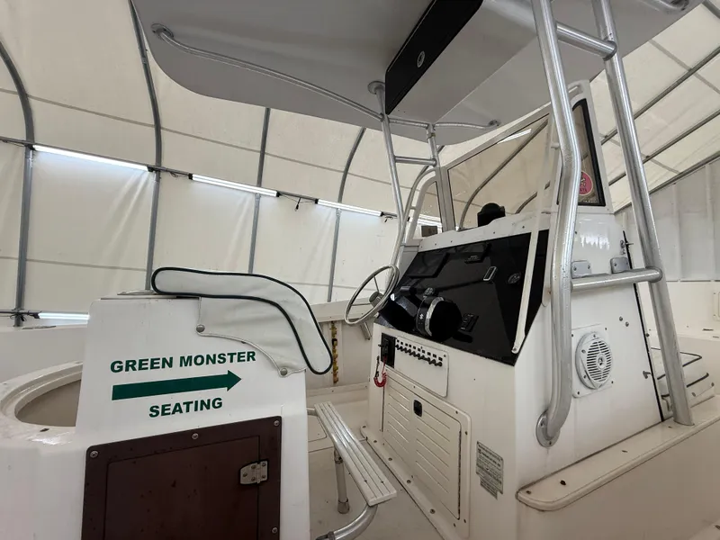 Slide: The Image of 1996 Mako 241 boat interior with "Green Monster Seating" sign, under a canopy. - 10