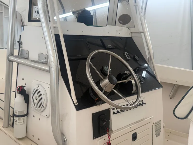 Slide: The Image of 1996 Mako 241 boat console with steering wheel and control panel. - 11