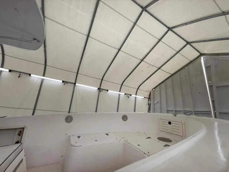 Slide: The Image of 1996 Mako 241 boat interior under a protective canopy, showcasing spacious seating and storage. - 15