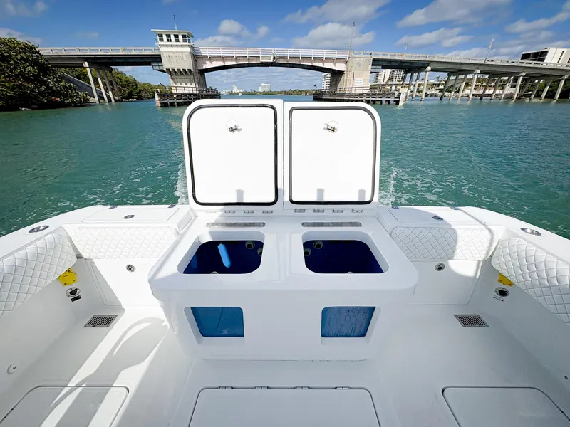 Slide: The Image of 2023 HCB 39 Speciale boat deck with open storage compartments, near a bridge over blue water. - 10