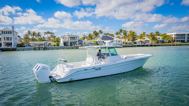 Slide: The Image of 2023 HCB 39 Speciale boat cruising on a sunny waterfront with luxury homes. - 3
