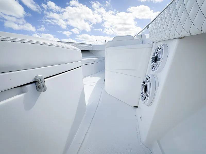 Slide: The Image of 2023 HCB 39 Speciale boat interior with white seating and speakers under a blue sky. - 32
