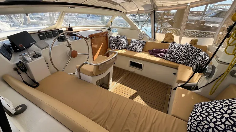 Slide: The Image of 1996 Amel Super Maramu-53 yacht cockpit with beige seating and patterned cushions. - 11