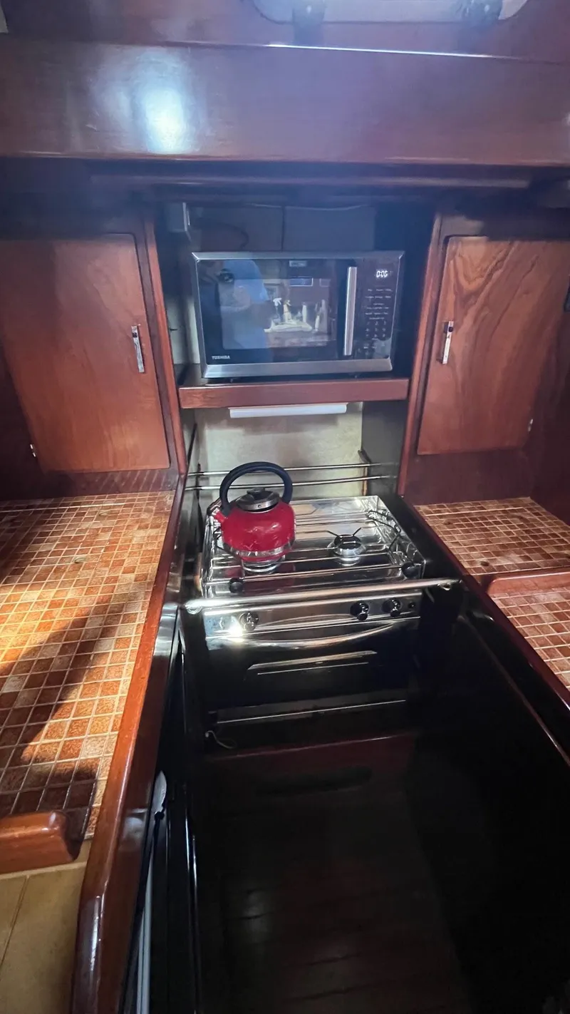 Slide: The Image of Galley kitchen in 1996 Amel Super Maramu-53 yacht with stove, microwave, and red kettle. - 24