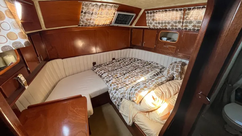 Slide: The Image of Cozy cabin interior of 1996 Amel Super Maramu-53 sailboat with wood paneling and patterned bedding. - 38