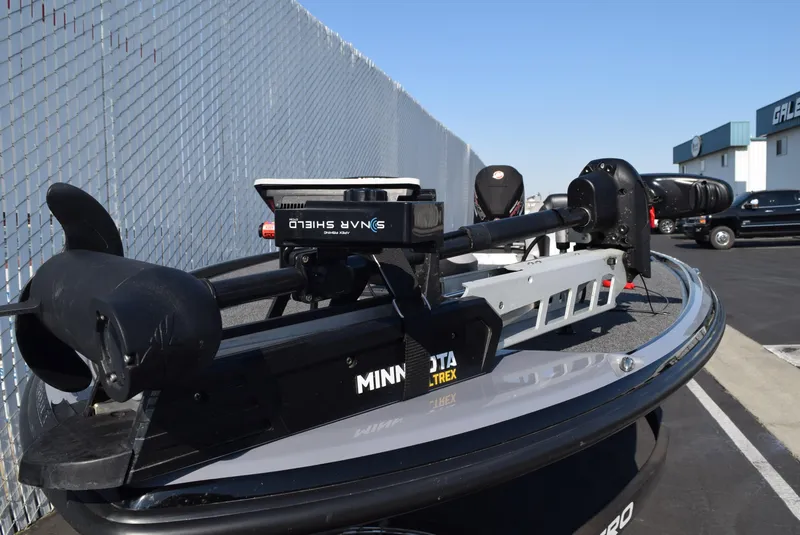 Slide: The Image of 2025 Nitro Z20 XL Pro boat with Minn Kota Ultrex motor, parked near a chain-link fence. - 8