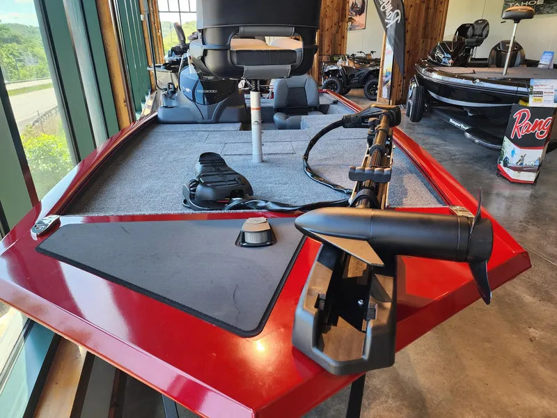 Slide: The Image of 2025 Tracker Pro 170 boat with red exterior and trolling motor, displayed indoors. - 2