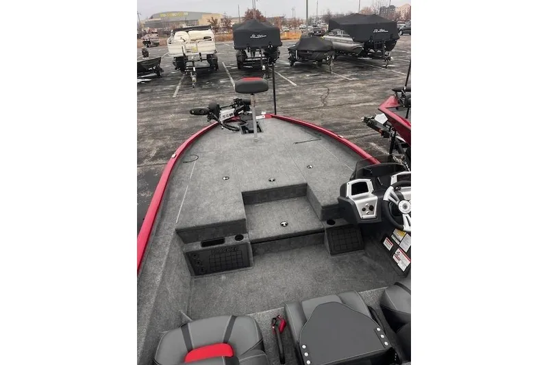 Slide: The Image of 2025 Tracker Savage 215 boat interior with seating and control panel in a parking lot. - 85