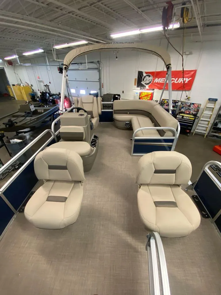 Slide: The Image of 2025 Sun Tracker Bass Buggy 16 XL Select pontoon boat with spacious seating in a showroom. - 2