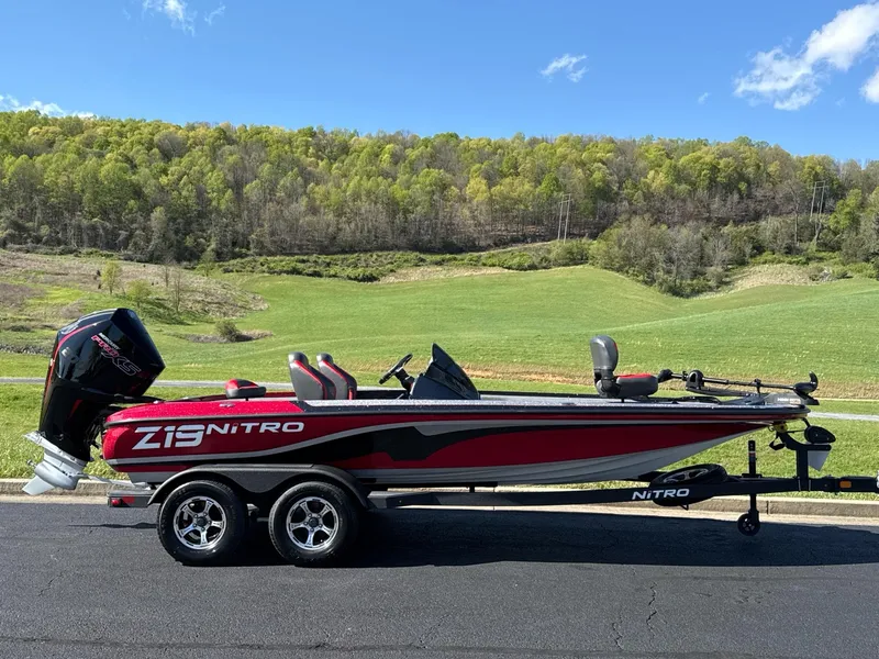 Slide: The Image of 2025 Nitro Z19 boat on trailer, scenic background with flags and hills. - 1