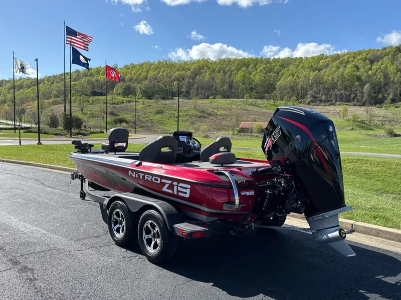 Slide: The Image of 2025 Nitro Z19 boat on trailer, parked on road with scenic green landscape. - 2