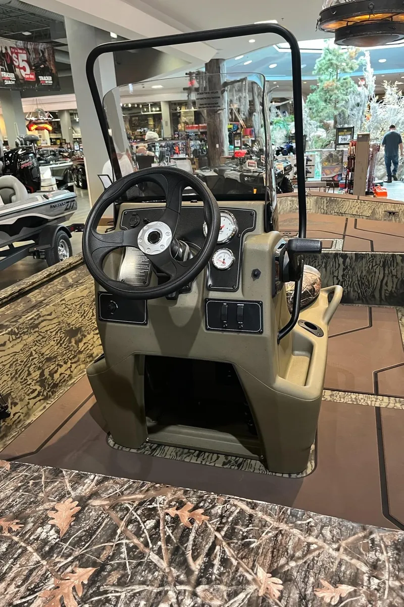 Slide: The Image of 2025 Tracker Grizzly 1860 CC boat interior with steering console and camouflage design. - 5
