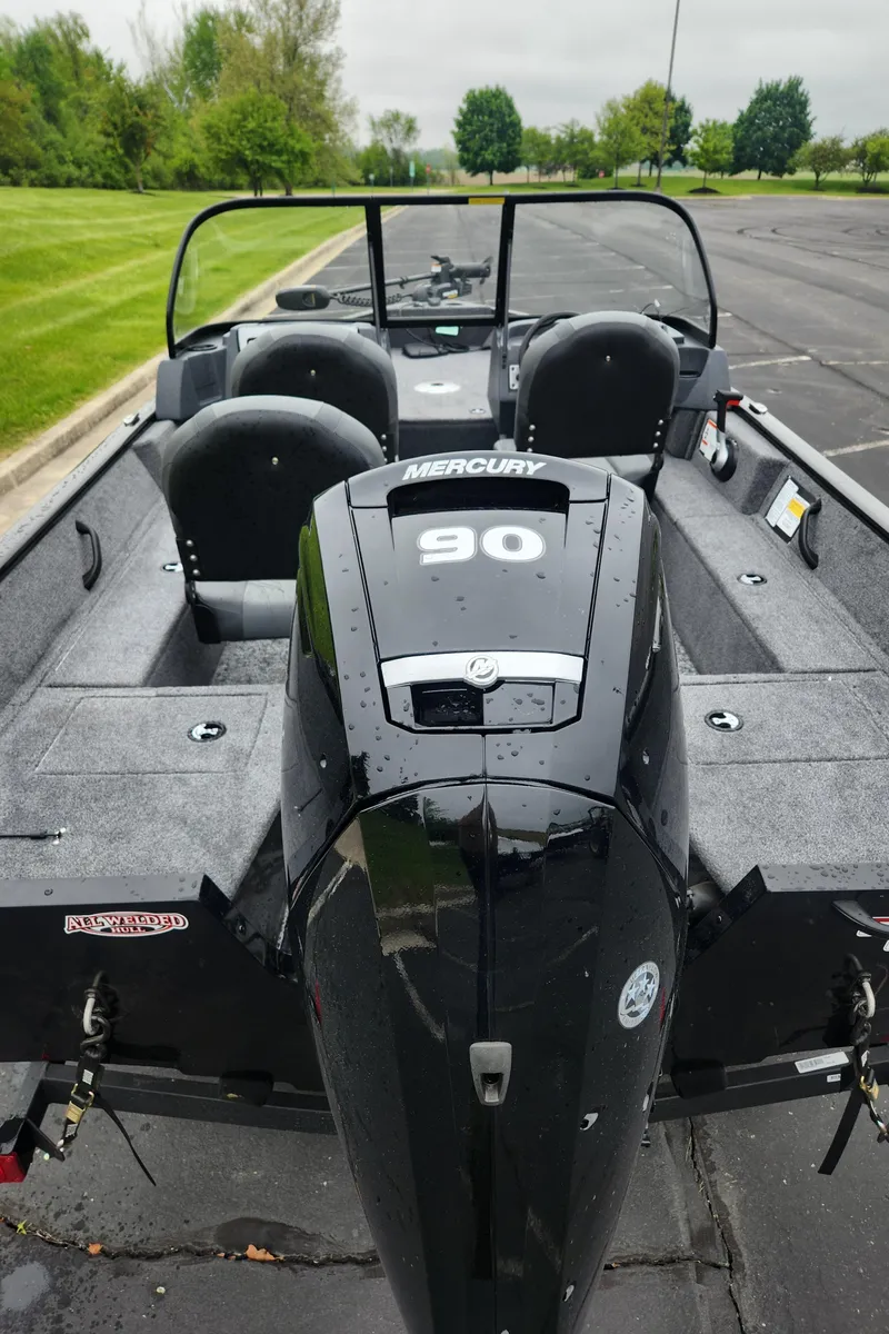 Slide: The Image of 2025 Tracker Pro Guide V-16 WT boat with Mercury 90 engine in a parking lot. - 2